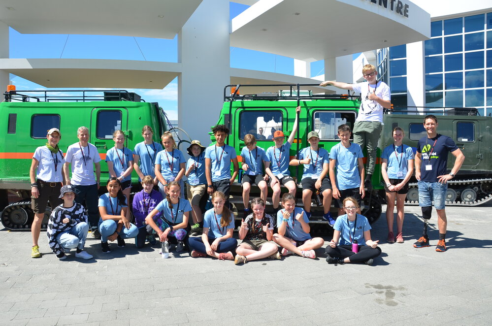 Full group photo of the Young Inspiring Explorers&trade; with Antarctic Heritage Trust staff and a Hagglund at the 2020 Summit