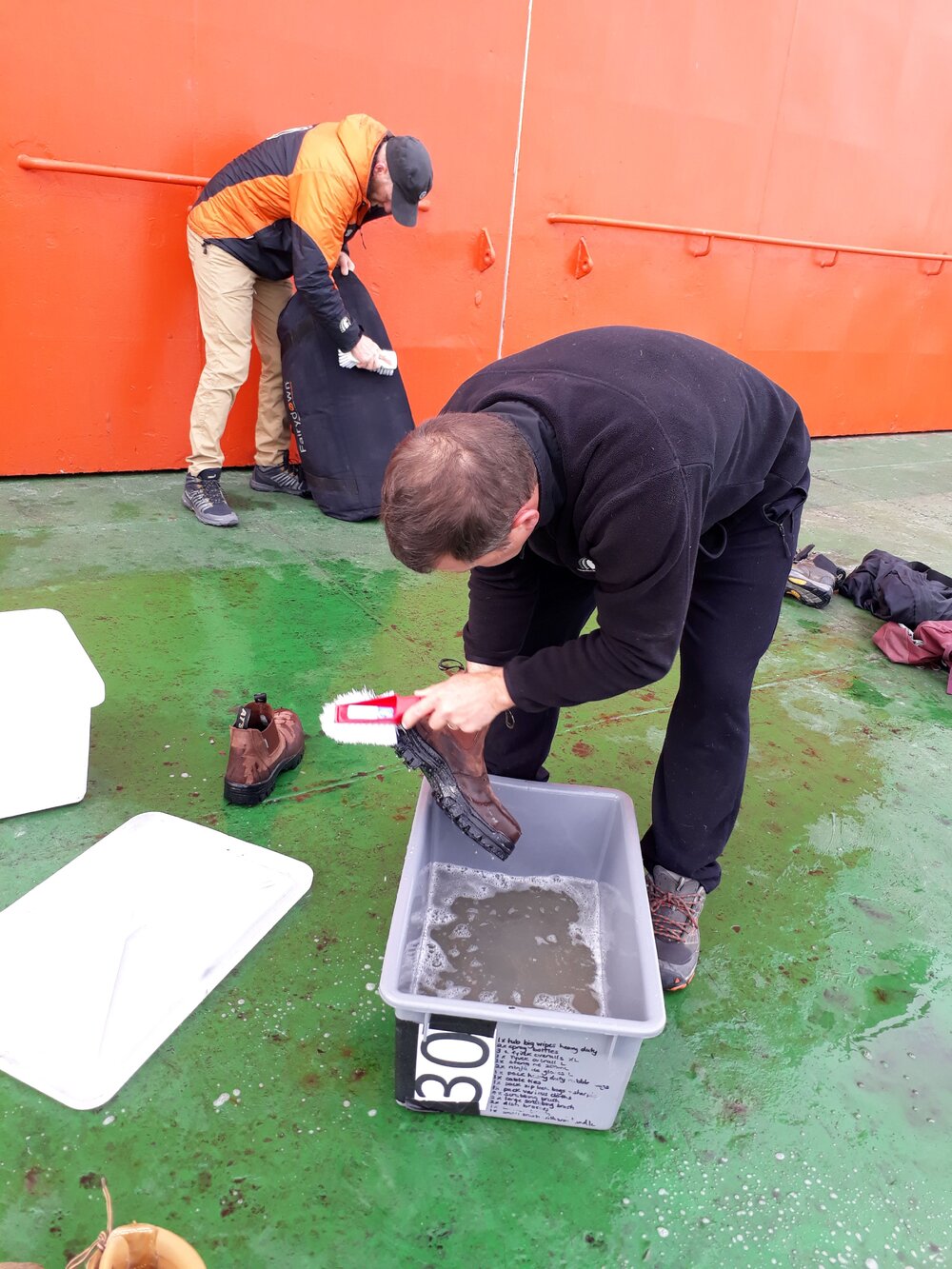 2019-20 AHT Executive Director Nigel Watson cleaning his shoes before landing at Cape Adare (001)