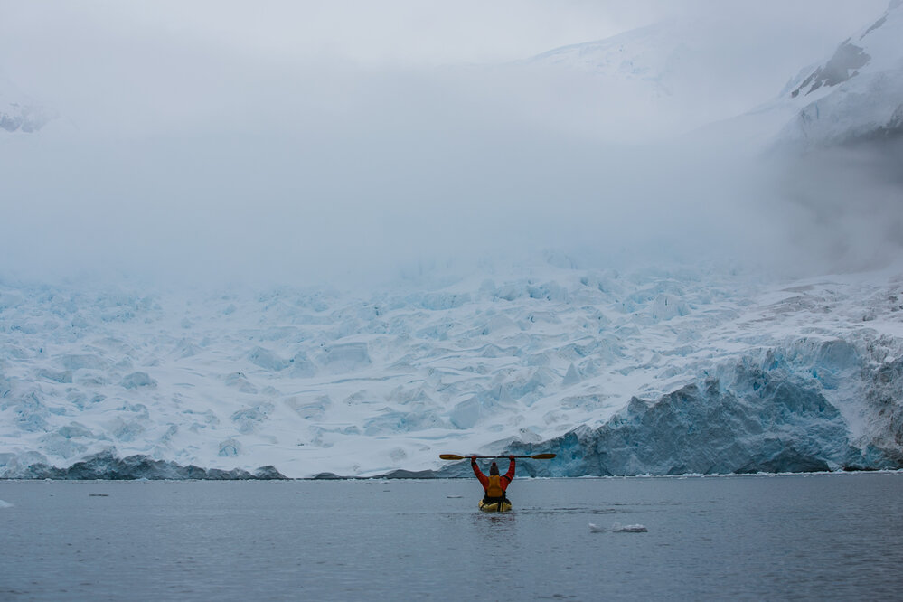 Inspiring Explorer Georgie Archibald kayaking in front of glacier