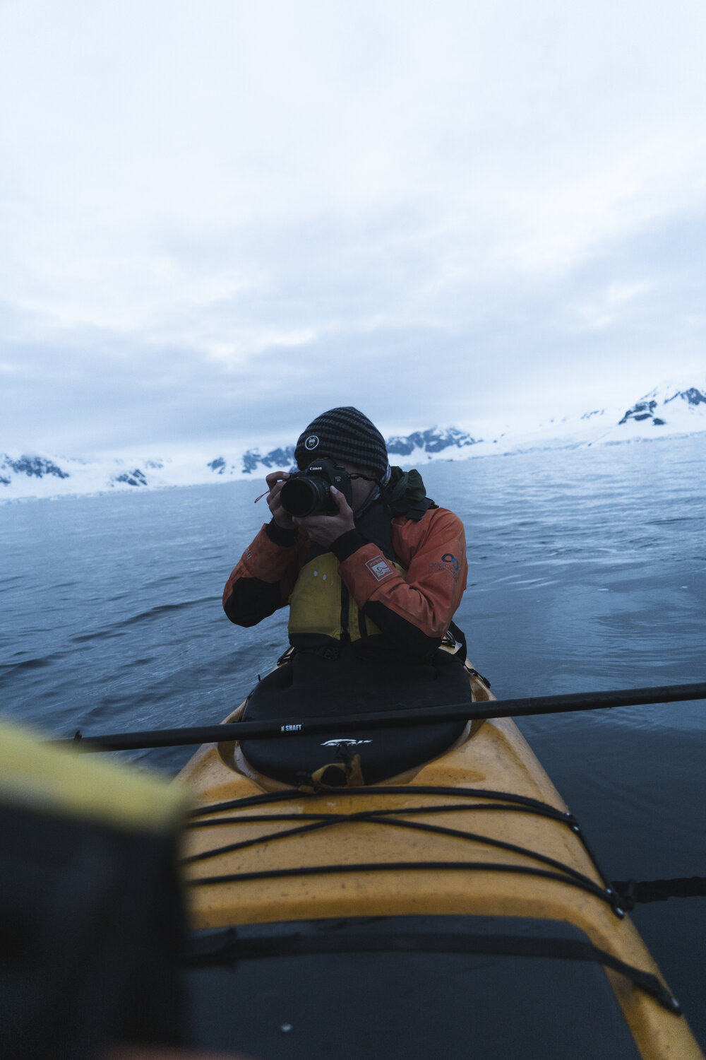 Alexander Hillary photographing from kayak on Antarctic Peninsula