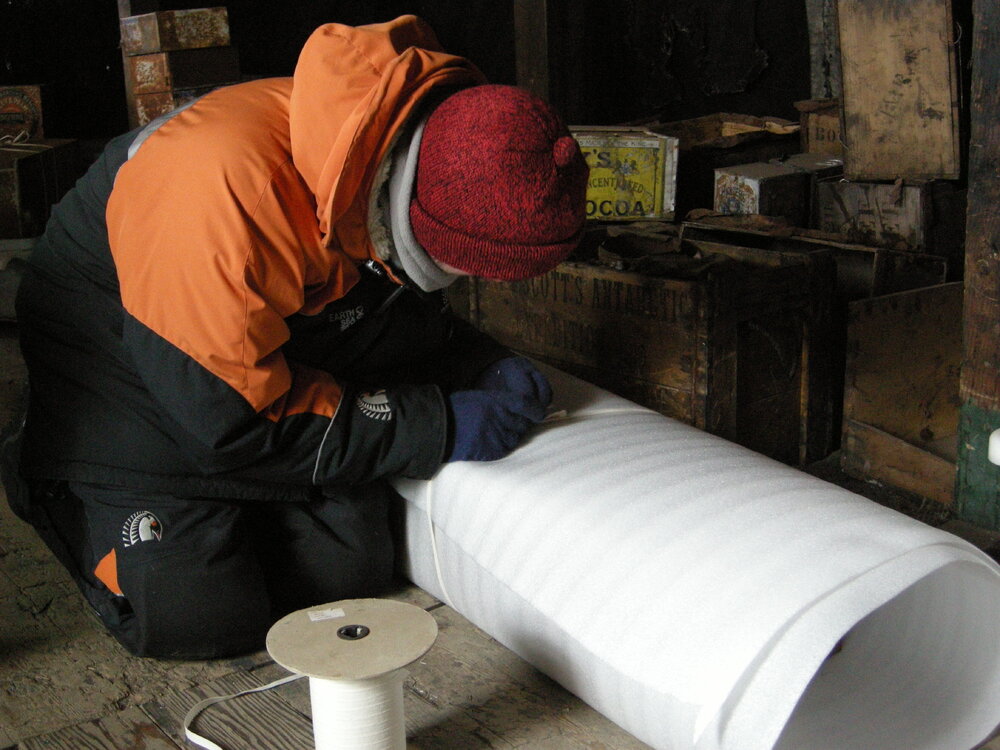 2013-14 Josiah Wagener wrapping artefacts inside Scott's 'Discovery' hut, Hut Point (002)