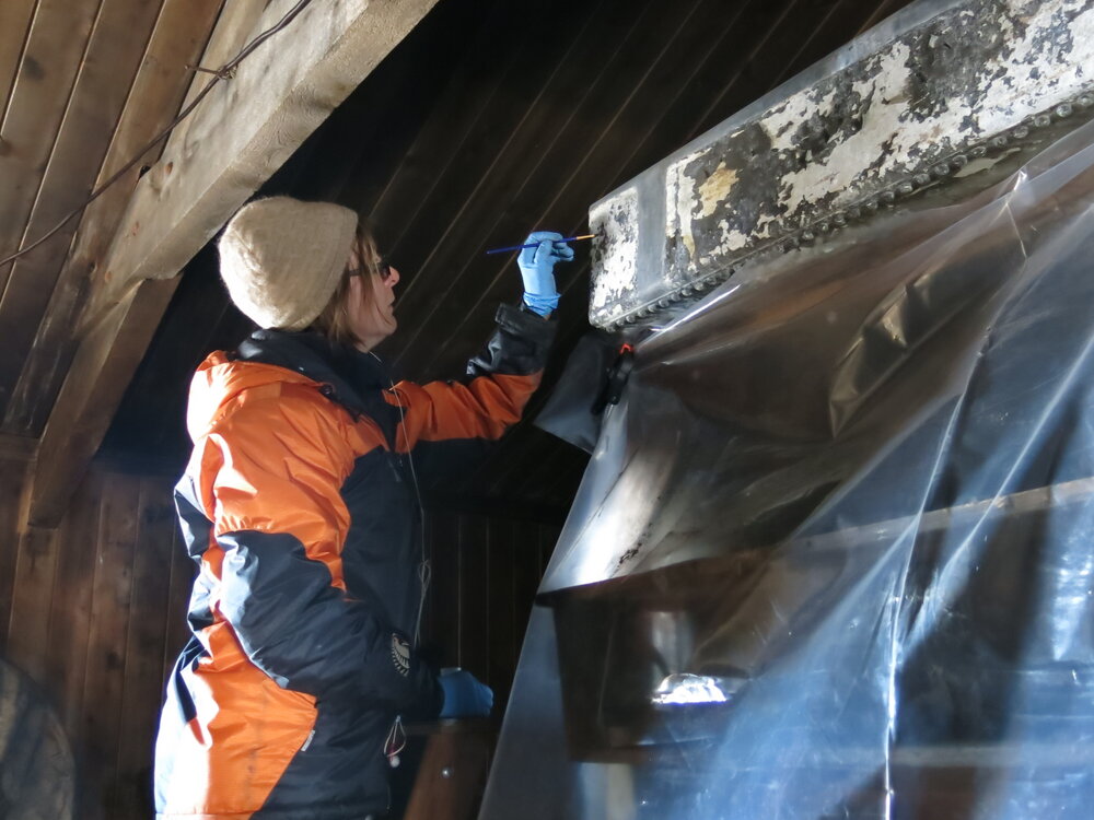 2013-14 Conservators at work. Nicola Dunn treating the water tank, Cape Evans (001)