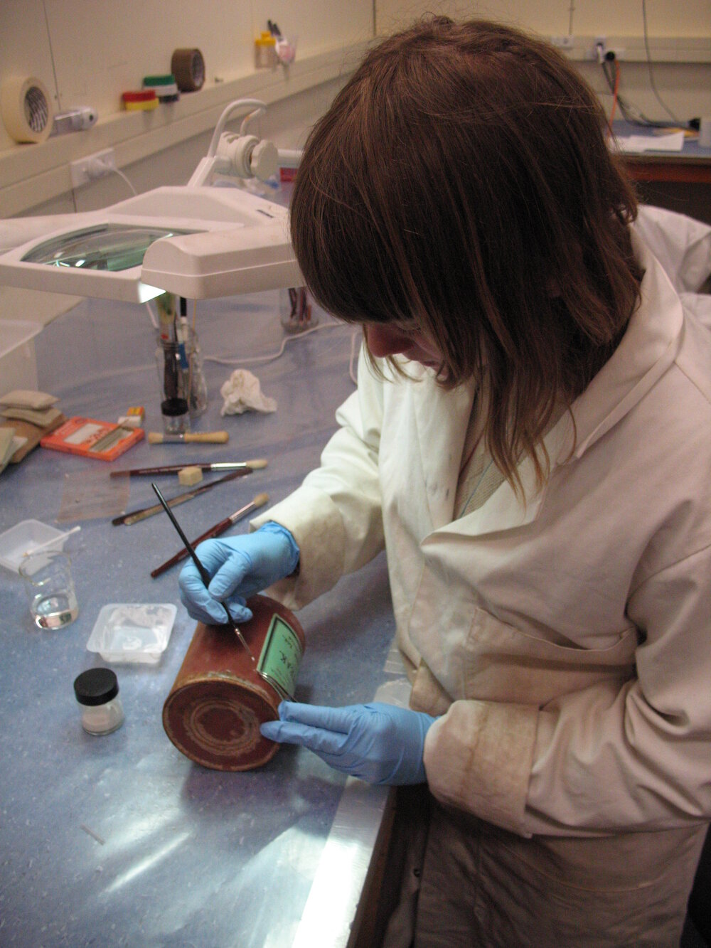 AHT Conservator Carla Pike pasting label to tin