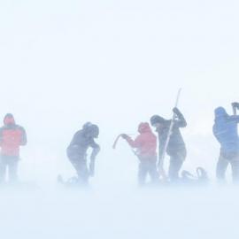 Inspiring explorers fighting to manage their climbing skins while taking them off in the wind during their crossing of South Georgia