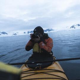 Alexander Hillary photographing from kayak on Antarctic Peninsula
