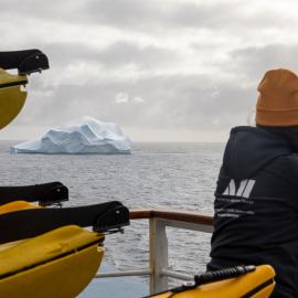 Inspiring Explorer Jaylee Savage viewing a large iceberg