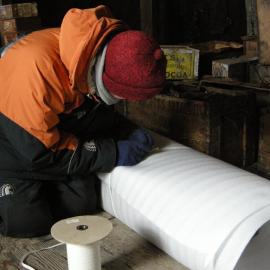 2013-14 Josiah Wagener wrapping artefacts inside Scott's 'Discovery' hut, Hut Point (002)