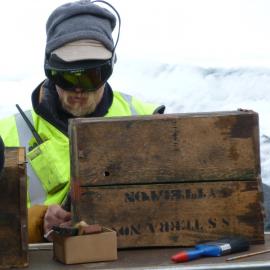 2010-11 Al Fastier treating a timber box outside, Cape Evans