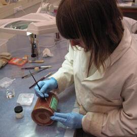 AHT Conservator Carla Pike pasting label to tin