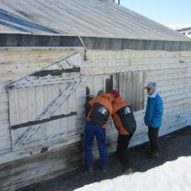 Inspecting window 4, Scott's 'Terra Nova' hut